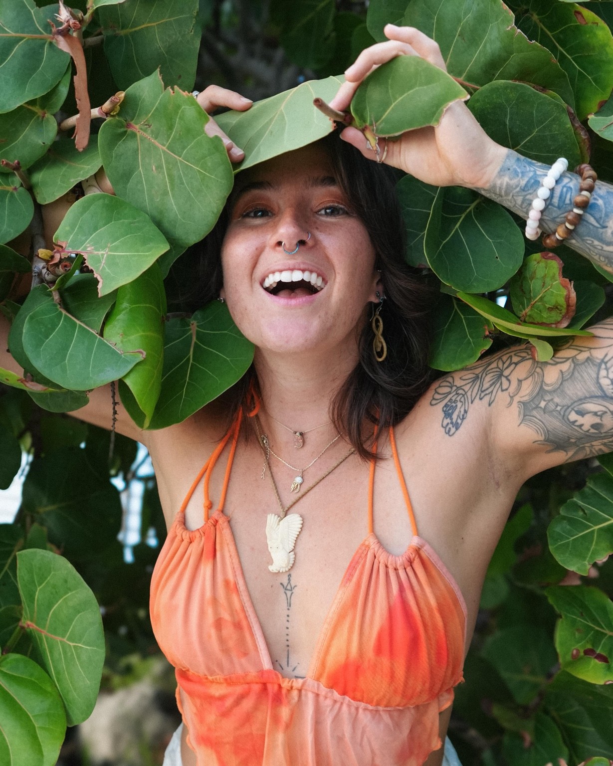 Megan Nardi laughing, framed by big round sea-grape leaves.