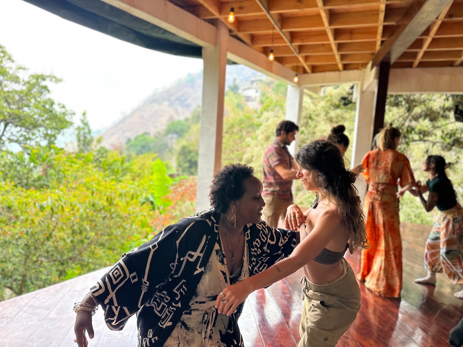 Megan dancing in contact with another mover on a porch, a wider group moving together in the background.
