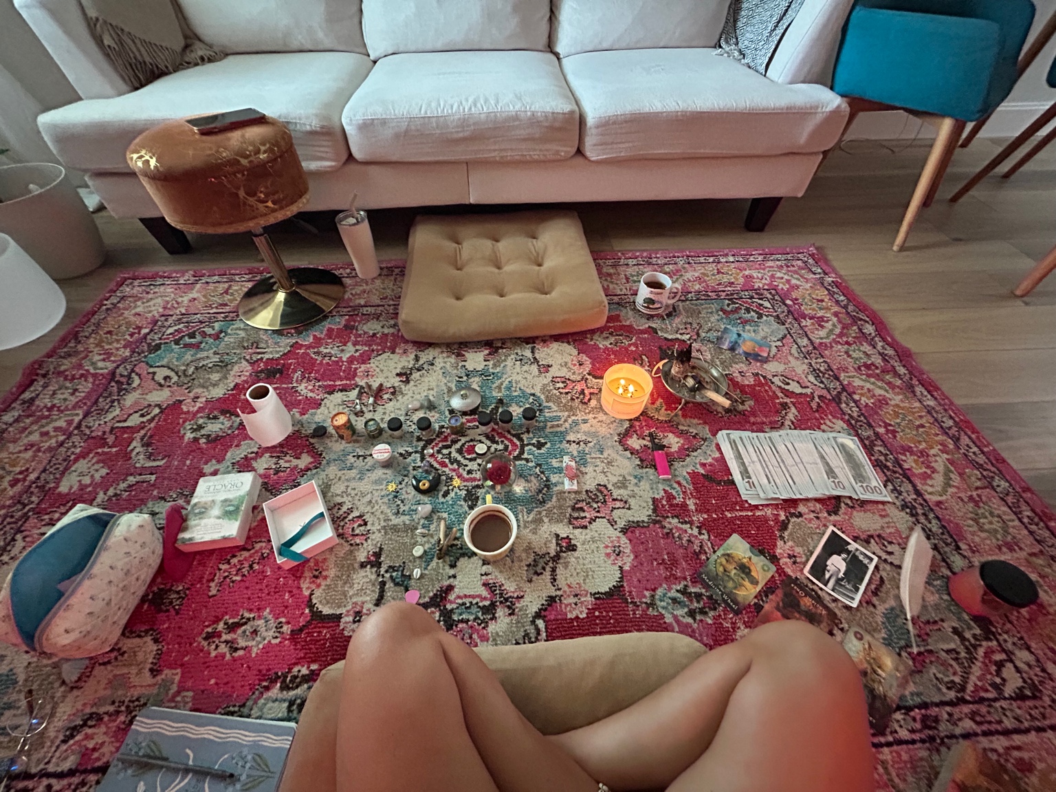 A held, intentional space set up on the floor — a candle, oracle cards, and a cup of cacao arranged with care.